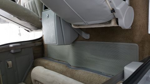 1995 Ford Bronco - The interior of the vehicle shows the floor mats, seats, and a storage compartment between the front seats.