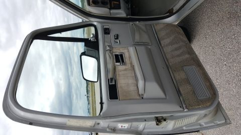 1995 Ford Bronco - View of the interior door panel and window, showing the fabric insert and side mirror.
