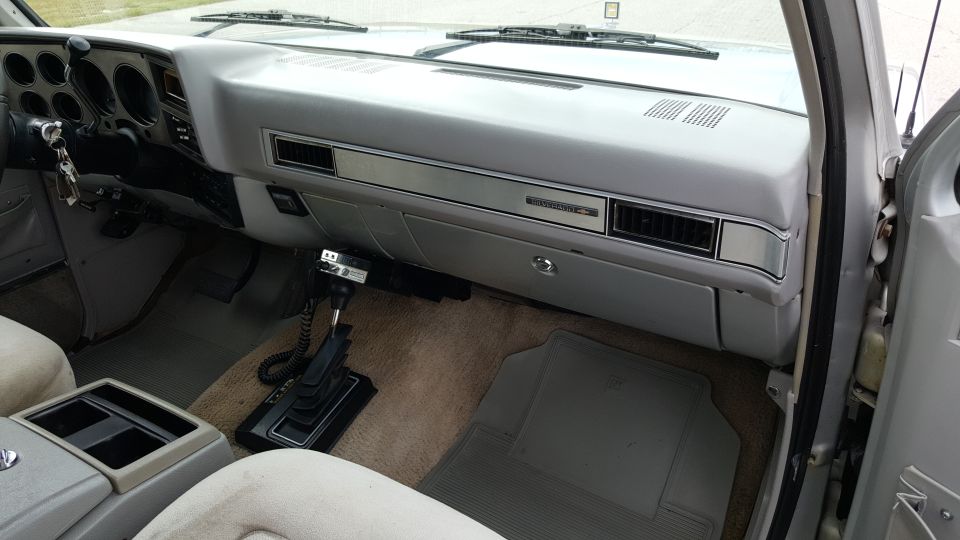 Interior view of a truck dashboard, showing the steering wheel, gauges, center console with gear shifter, and passenger seat