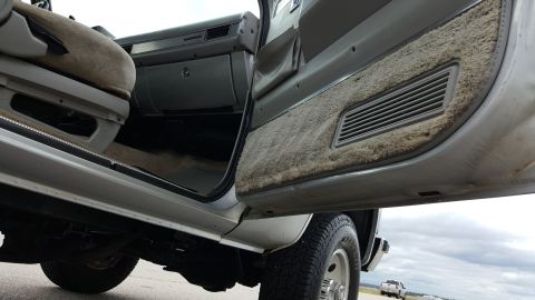 1995 Ford Bronco - The interior of a truck is shown with the driver's side door open, revealing the seat and dashboard area.