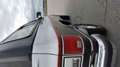 1995 Ford Bronco - This SUV, possibly a Chevrolet Suburban or similar model from the 1990s, features a two-tone paint scheme and prominent chrome accents.