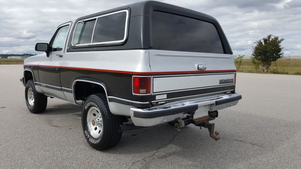 Rear 3/4 view of a silver and black two-tone SUV with a black hardtop
