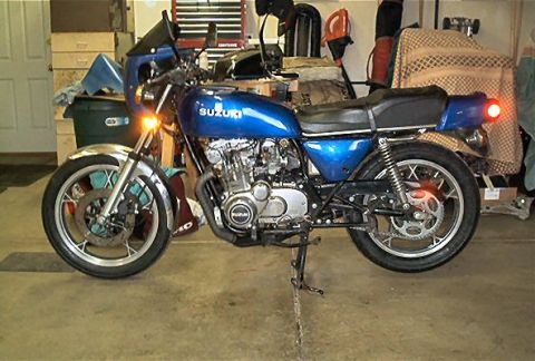 1985 Ford Crown Victoria LTD - A blue Suzuki motorcycle is parked indoors, showing its engine and side profile.