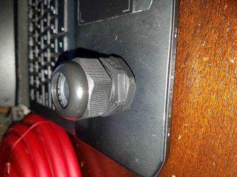 1994 Ford Bronco - A black cable gland is shown resting on a laptop keyboard, next to a spool of red wire.