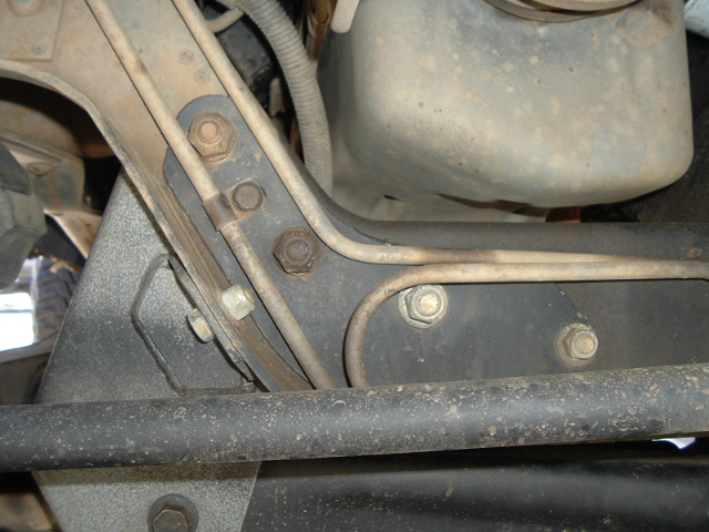 Dusty undercarriage frame bracket with hex bolts and metal canister above