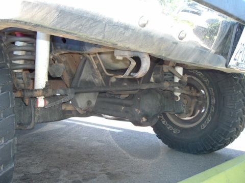 1989 Ford Bronco - The front axle and suspension components of a vehicle are visible from below.