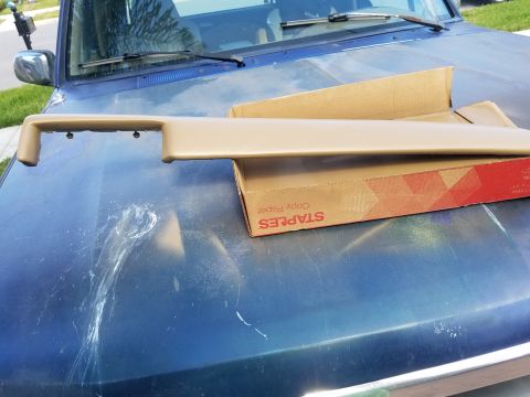 1994 Ford Bronco - Dashboard trim piece for a 1994 Ford Bronco resting on the vehicle's hood.