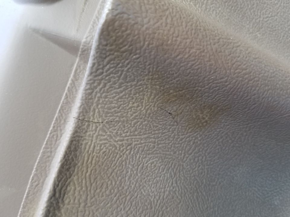Close-up of cracked, textured plastic trim on a vehicle's dashboard