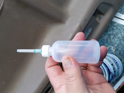 1994 Ford Bronco - A hand holds a precision oiler bottle against a vehicle's interior door panel.
