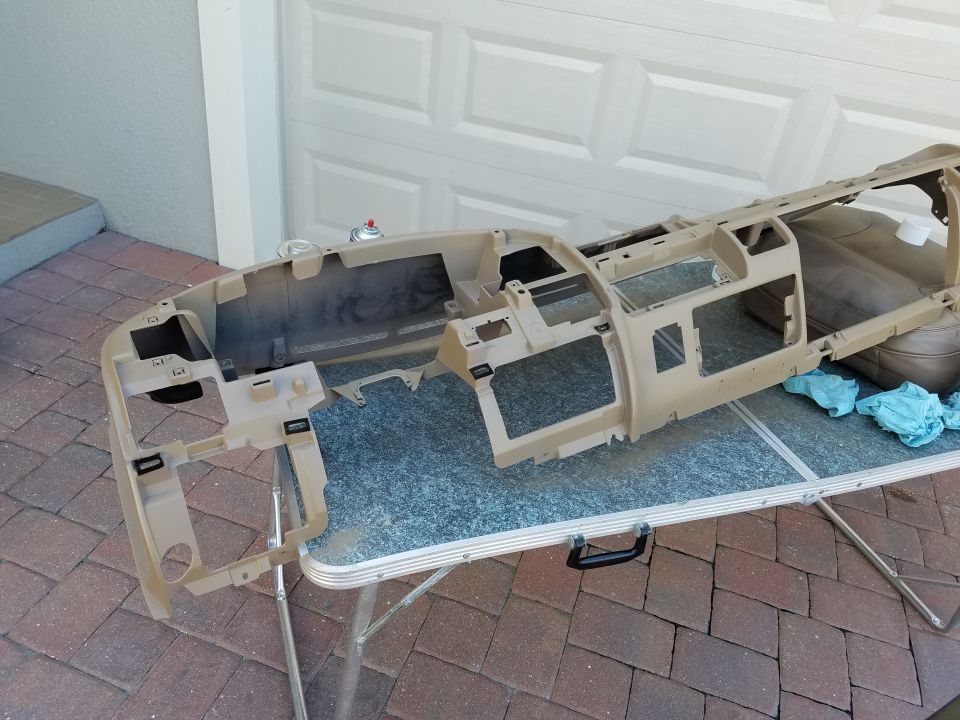 Tan dashboard frame for a 1994 Ford Bronco, sitting on a folding table outdoors