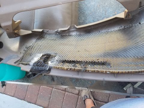 1994 Ford Bronco - Photo of a cracked and delaminated carbon-fiber composite panel being worked on outdoors.
