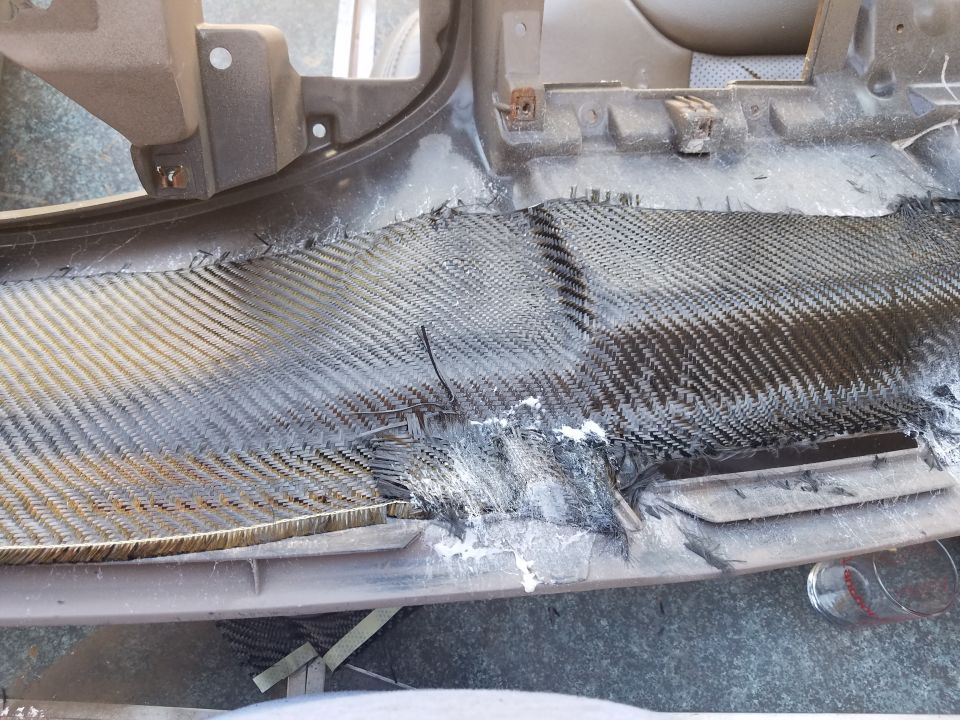 Damaged dashboard panel with carbon fiber repair patch and white adhesive