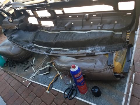 1994 Ford Bronco - Dashboard and seats removed for repair, with tools and adhesive nearby.