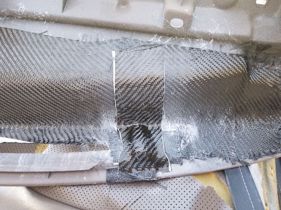Dashboard interior with carbon fiber patch repair, showing woven texture and torn edges