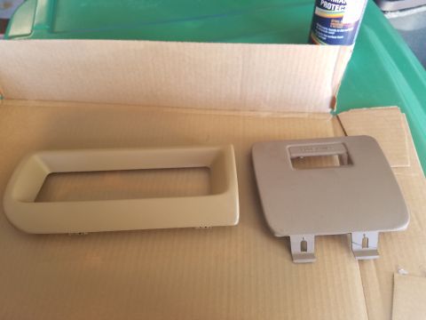 1994 Ford Bronco - Two interior car parts are laid out on a cardboard surface, ready for installation or repair.