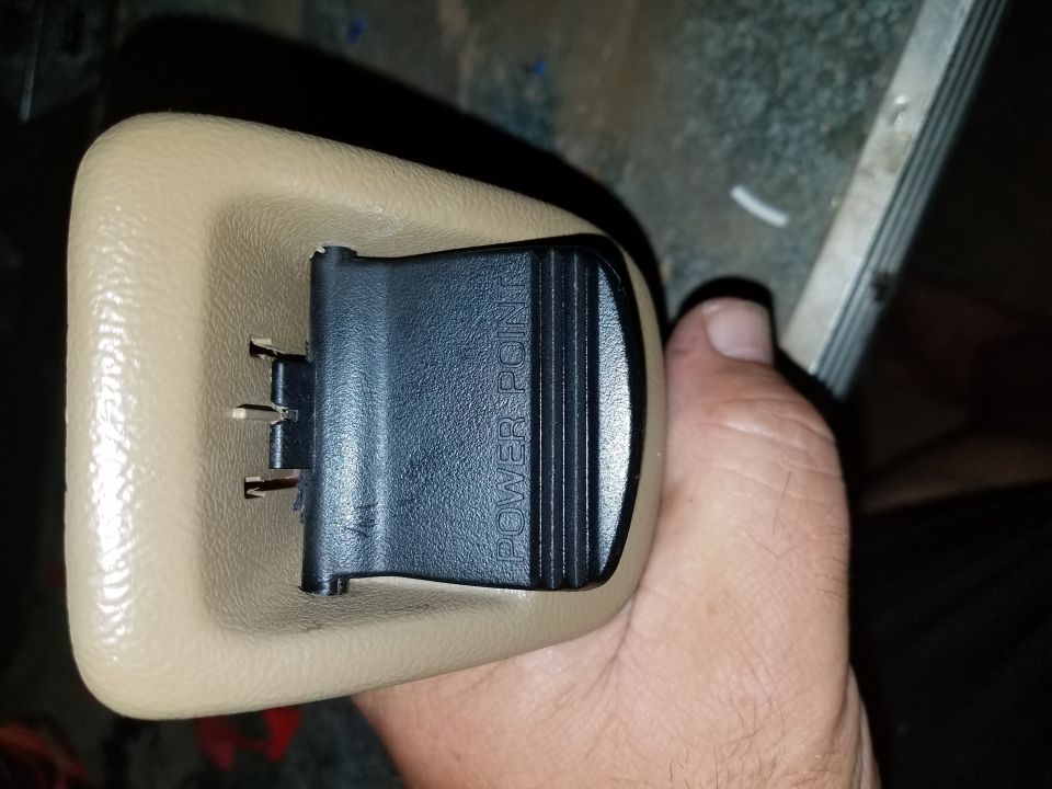 Tan interior trim piece with a black "POWER POINT" switch held in a hand