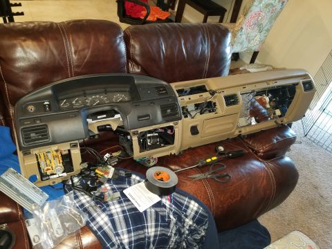 1994 Ford Bronco - A vehicle's dashboard is disassembled, with various parts and tools laid out on a brown leather couch.
