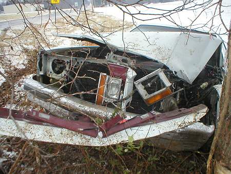 1989 Ford Crown Victoria - The front end of a 1989 Ford Crown Victoria is severely damaged after a collision, with the hood crumpled and headlights broken.