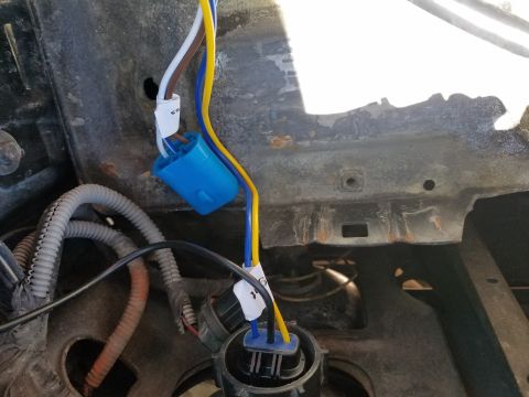 1994 Ford Bronco - This image shows a close-up view of a vehicle's headlight wiring harness, including connectors and wires.