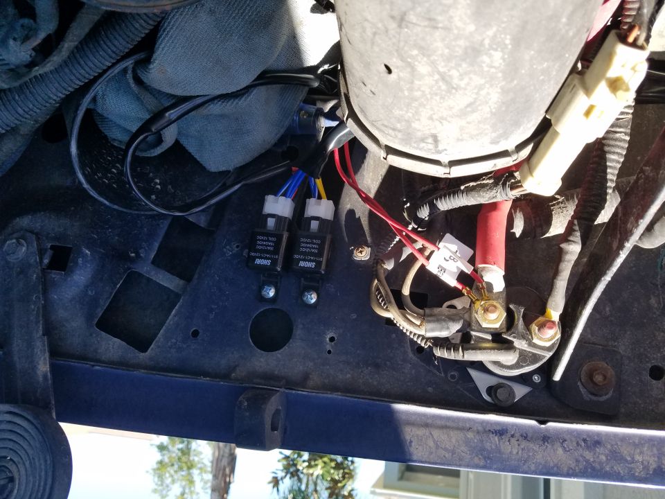 Headlight relays and wiring harness under a vehicle