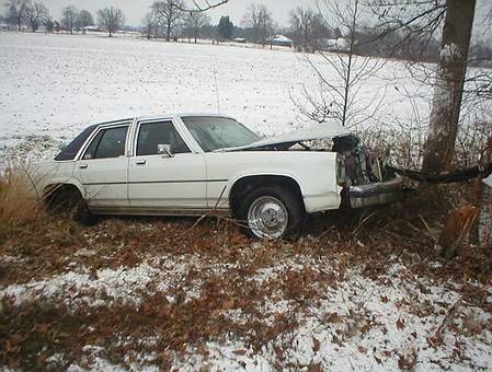 1989 Ford Crown Victoria - White 1989 Ford Crown Victoria sustained significant front-end damage after colliding with a tree in a snowy area.
