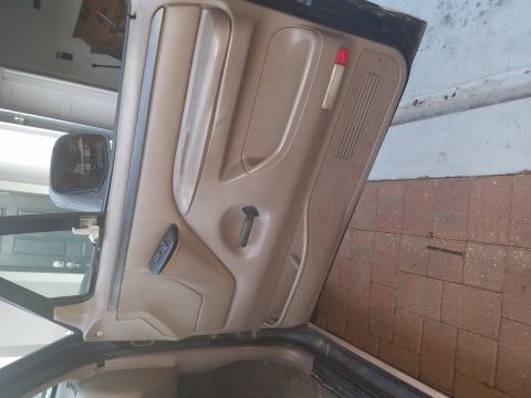 1994 Ford Bronco - Close-up of a vehicle's interior door panel, showing the armrest, door handle, and window controls.