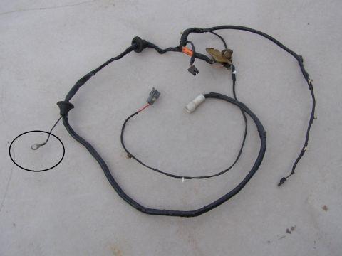 1994 Ford Bronco - Vehicle wiring harness laid out on a concrete surface, showing various connectors and a ground lug.