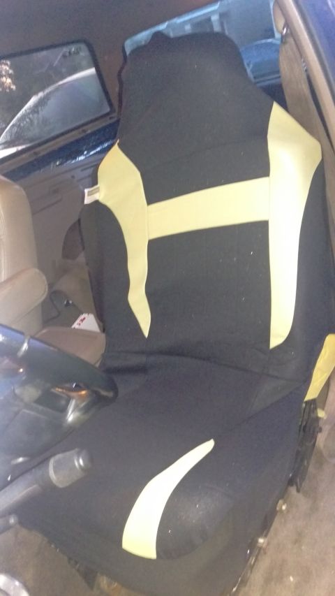 1994 Ford Bronco - Interior view of a vehicle's driver seat, covered in a black and yellow seat cover.