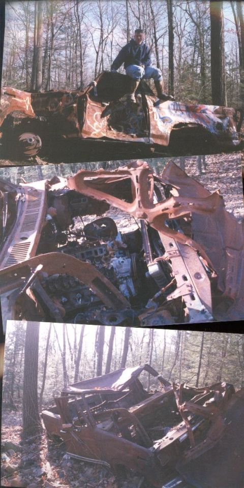 1978 Ford Bronco - A heavily damaged and burnt vehicle sits in a wooded area, with a person perched on its roof.