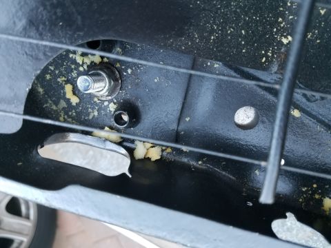 1994 Ford Bronco - Close-up view of a seat mounting bracket, showing a bolt and some yellow foam debris.
