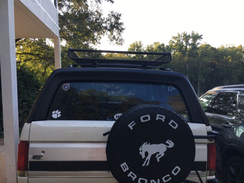 Rear of white Ford Bronco with spare tire cover and roof rack