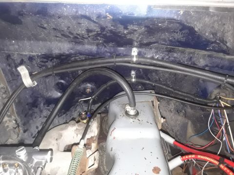 1985 Ford Bronco - Close-up view of engine bay components, including hoses and wiring, with visible water stains.