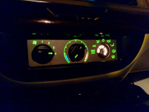 1995 Mercury Grand Marquis - Climate control panel with illuminated knobs and icons for fan speed, A/C, and air flow.