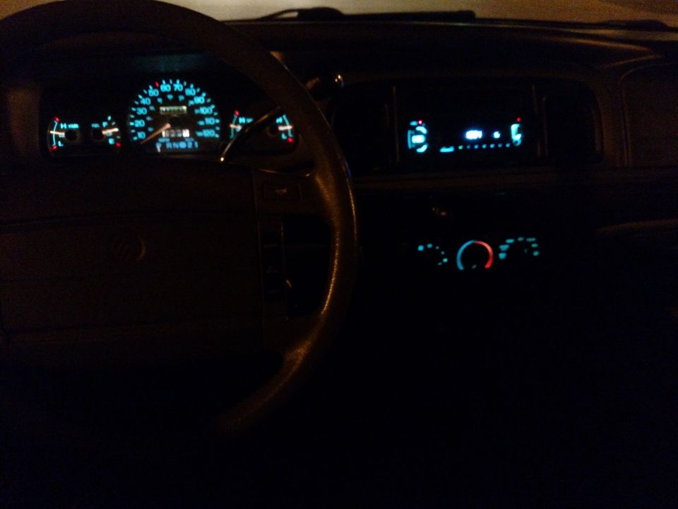 Car dashboard at night with illuminated gauges and radio display