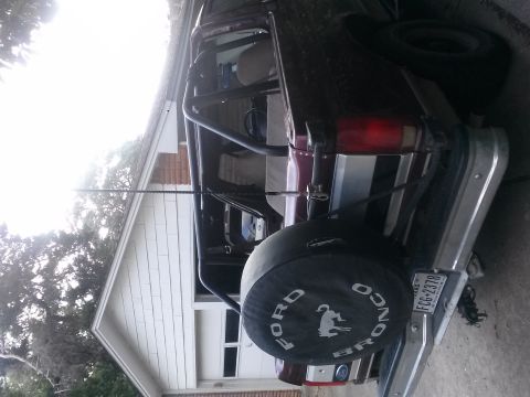1996 Ford Bronco - The rear view of a Ford Bronco shows a spare tire mounted externally, with a Texas license plate attached.