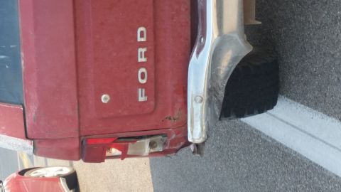 1981 Ford Bronco - Close-up of a red Ford tailgate showing the 'FORD' lettering and a damaged taillight assembly.