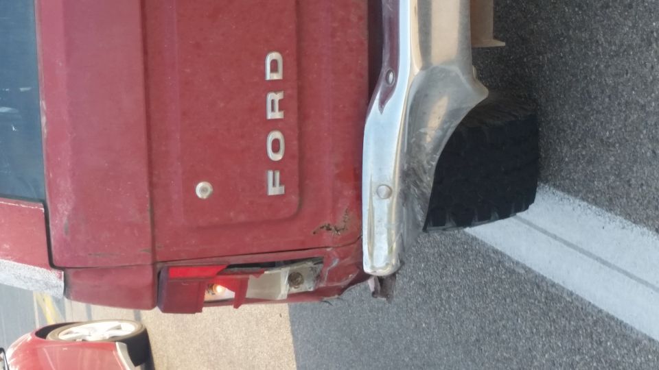 Red Ford tailgate with chrome bumper and damaged taillight. 1981 Ford Bronco