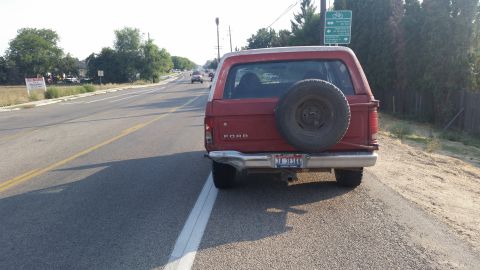 1981 Ford Bronco - The rear view of a red Ford Bronco shows a spare tire mounted externally and a license plate reading 'TI 361F'.