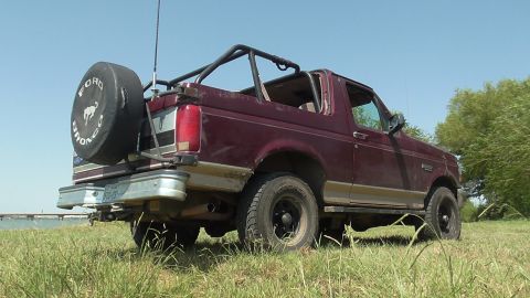 1996 Ford Bronco - Maroon 1996 Ford Bronco with a spare tire on the rear, parked outdoors.