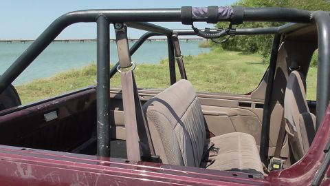 1996 Ford Bronco - Interior view of a 1996 Ford Bronco, equipped with a roll cage, parked near a body of water.