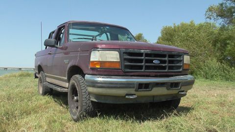 1996 Ford Bronco - This 1996 Ford Bronco is captured in a three-quarter front view, parked outdoors on a grassy area.