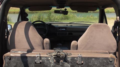 1996 Ford Bronco - The interior of a Ford Bronco is shown, with a view of a lake and grassy area through the windshield.
