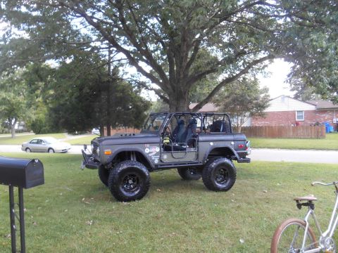 1972 Ford Bronco - This lifted 1972 Ford Bronco features a full roll cage and off-road tires, parked in a residential yard.