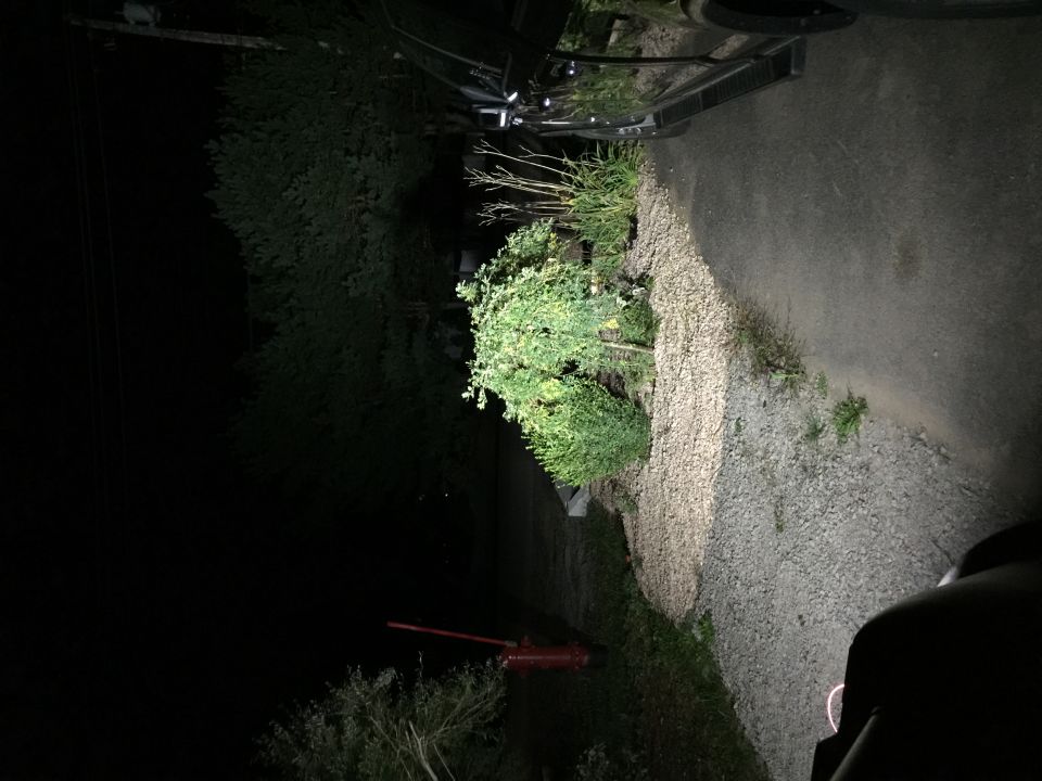 Vehicle parked on gravel driveway at night, headlights on