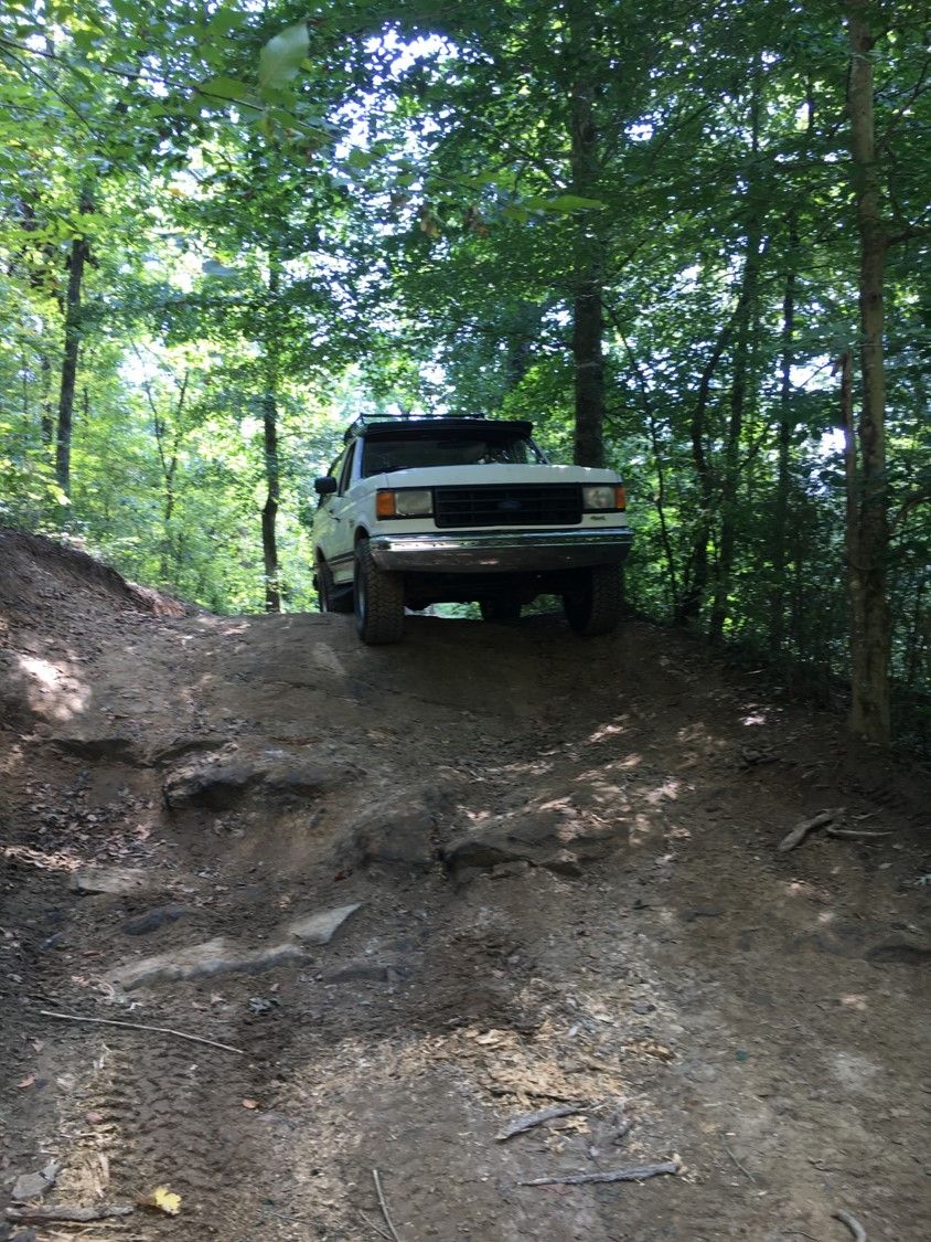 1988 Ford Bronco climbing a steep, rocky, wooded trail