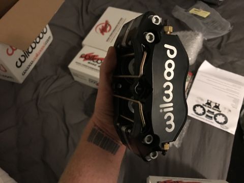 1973 Mazda RX-3 - A black Wilwood brake caliper is shown, with boxes and paperwork visible in the background.
