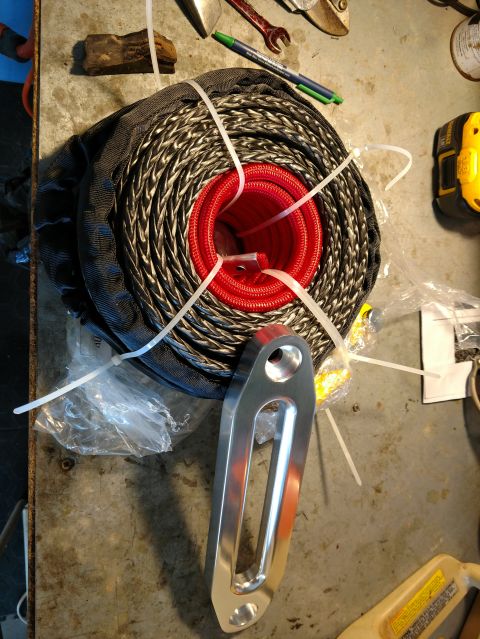 1992 Ford Bronco - A winch rope and hawse fairlead are laid out on a workbench, along with tools and zip ties.