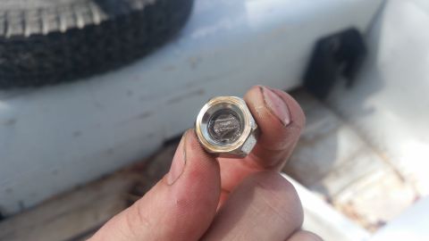 1981 Ford Bronco - Close-up of a lug nut being held by a hand, with a tire and part of a vehicle visible.
