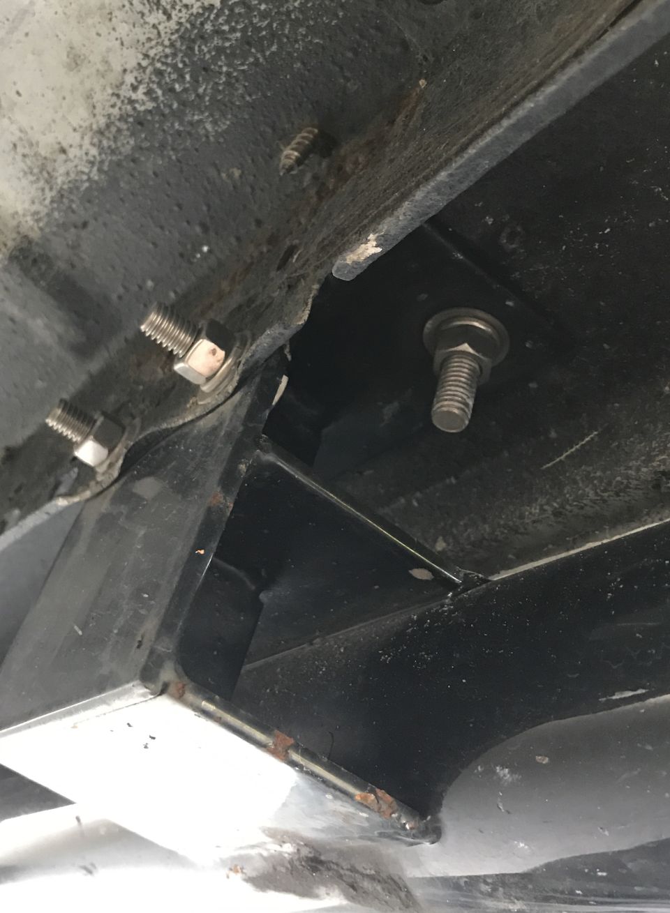 Close-up of rusted frame section with several bolts visible