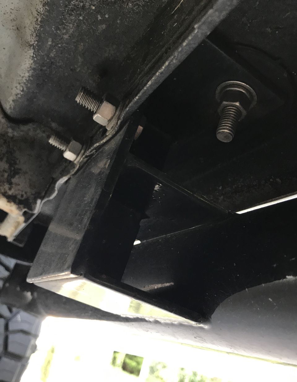 Undercarriage of a vehicle with black metal brackets and bolts visible